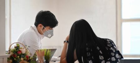 Photo of young couple that wearing a medical mask sitting and relaxing together at the wooden...