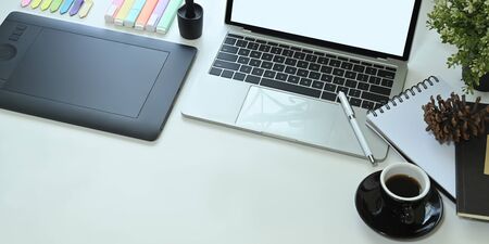 The top view image of the white working desk is surrounding by a computer laptop and graphic...