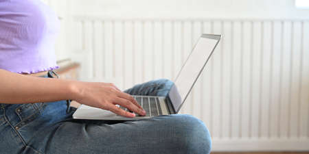 Cropped image of a woman's hands is typing on a computer laptop that putting on her lap.