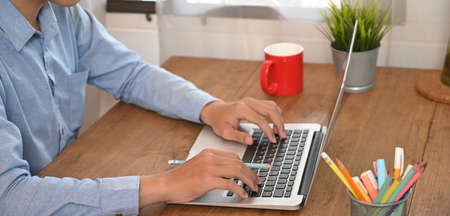 The graphic designer is working with a computer at the wooden working desk.