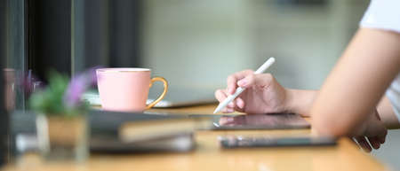 A cropped image of a woman is using a mobile phone at the wooden working desk.の写真素材