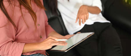 A schoolgirl is using a white blank screen computer tablet and stylus pen at the sitting room.の写真素材