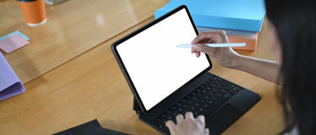Cropped image hands are using a computer laptop while sitting at the wooden working table.