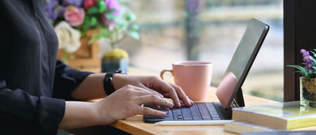 Computer tablet with a white blank screen is putting on a working desk surrounded by various...