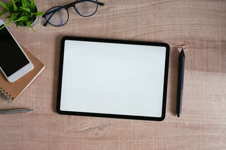 A woman is using a white blank screen computer laptop at the cluttered working desk.の写真素材