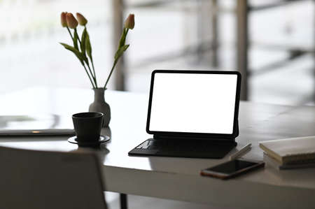 A beautiful woman is using a computer tablet with a white blank screen while sitting at the wooden counter bar.の写真素材