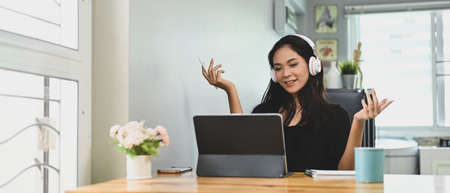 Office women are working together at the wooden working desk over a meeting room as a background.