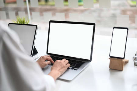 Creative workspace with empty screen computer, coffee, pencil and tulip flower on white table.の写真素材