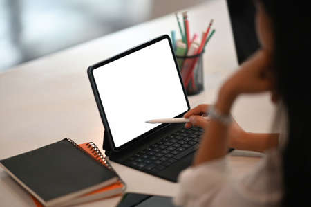 Creative workspace with empty screen computer, coffee, pencil and tulip flower on white table.