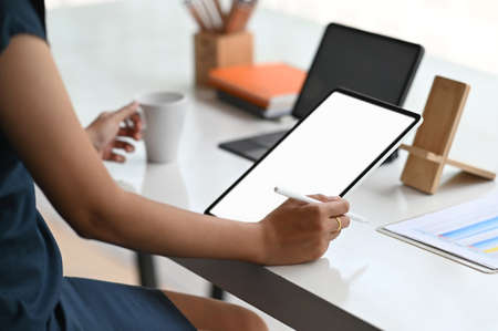 Woman holding empty screen blank screen tablet on wooden office desk.