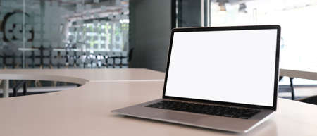 Modern work space, laptop with white screen, coffee cup and note book on white table.