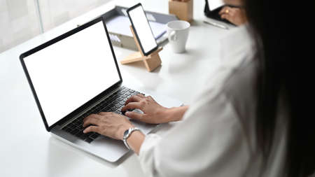 Modern work space, laptop with white screen, coffee cup and note book on white table.