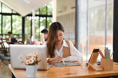 Portrait of attractive young businesswoman planing her project with tablet in modern office.の写真素材