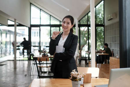 Young attractive businesswoman in black suit sitting and using smart phone in her office.の写真素材