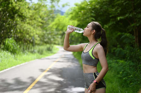 Portrait of Young sportswoman stretching her arms after jogging at the park.の写真素材
