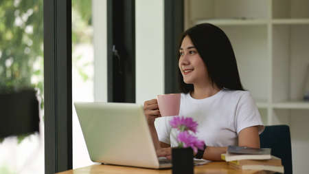 Portrait of businesswoman working on digital tablet with stylus pen while sitting on worktable in...