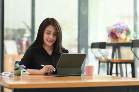 Young beautiful girl using digital tablet and smiling while sitting on sofa at home.