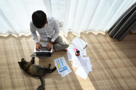 Top view of man working from home with laptop on the floor.