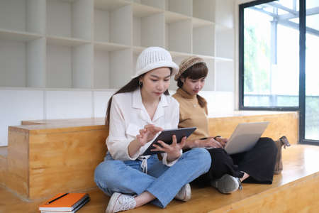 Two happy businesswomen coworking with a laptop in modern office.