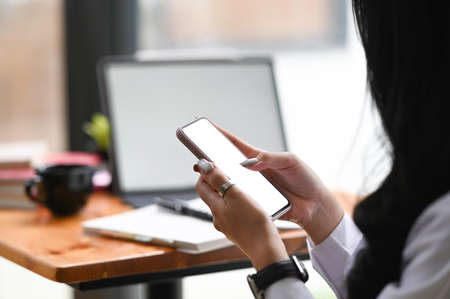 A professional businesswoman using smartphone in her office room.