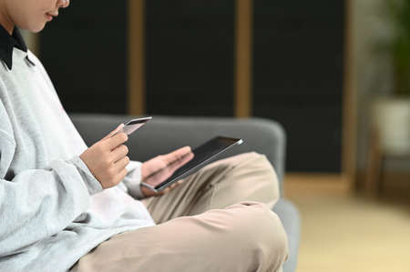 Cropped shot of young woman relaxing on comfortable couch while using laptop at home.