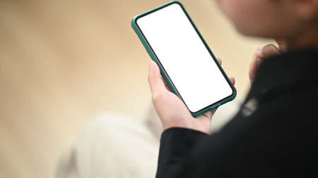 Close up view of female holding blank screen smartphone in office room.