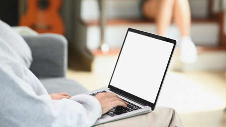 Cropped shot of young woman relaxing on comfortable couch while using laptop at home.