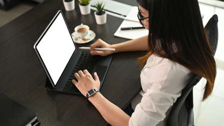 Cropped shot of young female working on her project with mock up tablet in meeting room.