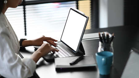 Cropped image of  businesswoman using mockup cellphone gadget with  blank screen on her work space.