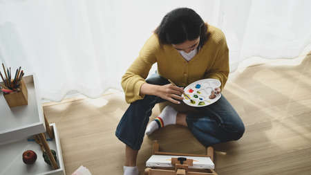 Portrait of a young female artist is painting on canvas in studio.の写真素材