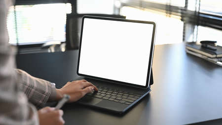 Cropped shot of using digital tablet while sitting at her working place.の写真素材