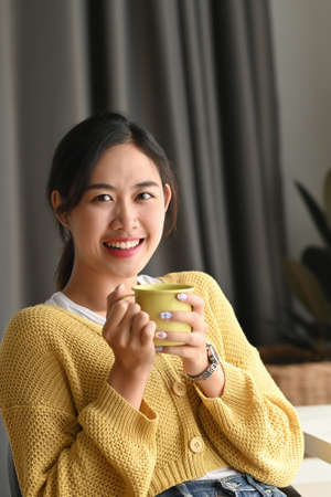 Portrait of a woman hands holding cup of hot beverage and smiling to camera in office.