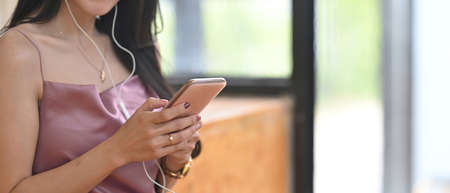 Young woman girl using smartphone earphones listening to music or having fun watching video.