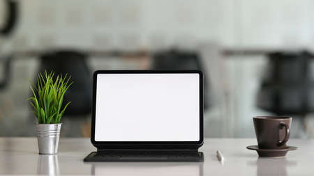 Desktop computer tablet on workspace table showing blank white screen for products or graphic...