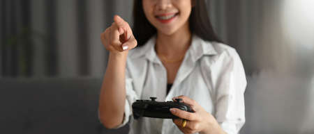 A young female is using tablet during listening to music on a wireless headphone while lying on sofa...
