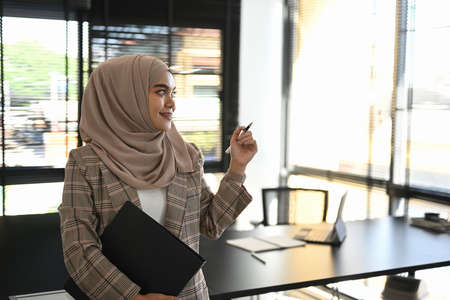 Portrait of young Arabic business woman wearing hijab in front of laptop search and doing office work.の写真素材