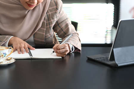 Portrait of young Arabic business woman wearing hijab in front of laptop search and doing office work.の写真素材