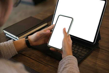 Cropped shot of woman hands using mobile phone and tablet computer with blank copy space screen for...