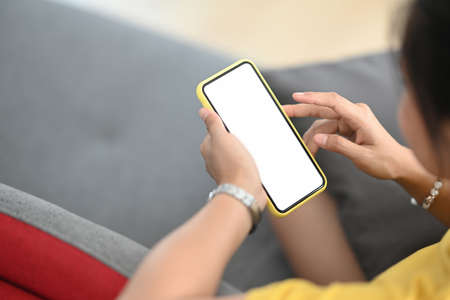 Close up view of woman hands holding mobile phone with blank white screen for graphic display...