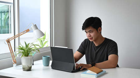 A young designer analyzing data on computer tablet at work space.
