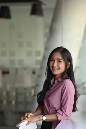 Portrait of a businesswoman is sitting at her desk in an office while looking at camera and smiling.