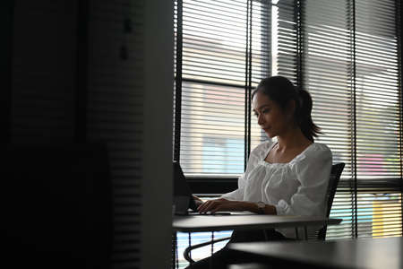 A young confident businesswoman employee is typing email on computer tablet at workplace.の写真素材