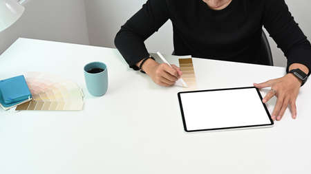 Cropped shot of a businessman is working on computer tablet and checking financial report at the...