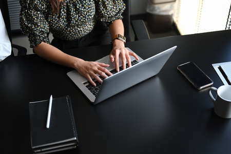 An open laptop with blank screen on wooden table and blur modern meeting room background.