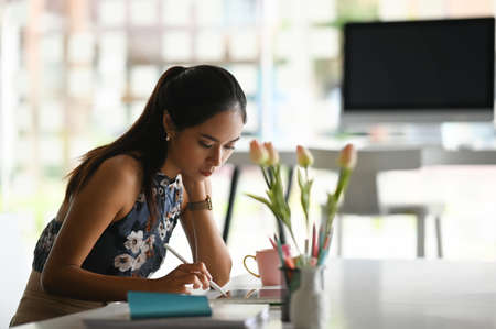 Young woman hands holding stylus pen and writing information on digital tablet.のeditorial素材