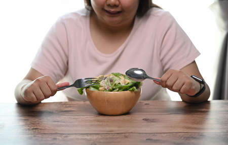 Cropped shot of overweight woman is eating vegetarian salad for weight loss and health.の写真素材