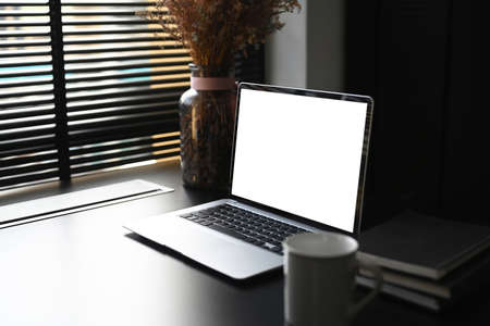 Close up of a female hands busy typing on a laptop with blank screen at her workspace.