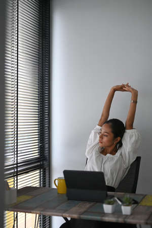A businesswoman resting at her workspace satisfied after work done.
