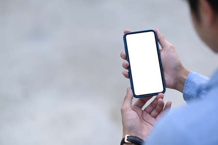 Crose up view of businessman reading information on cell telephone. Blank screen mobile phone for...