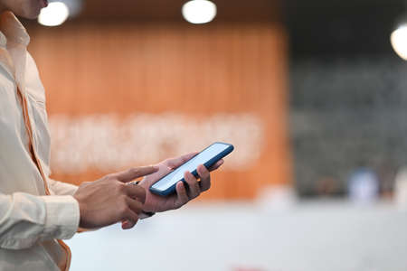 Cropped shot of businessman hands using smartphone mockup at his workplace.